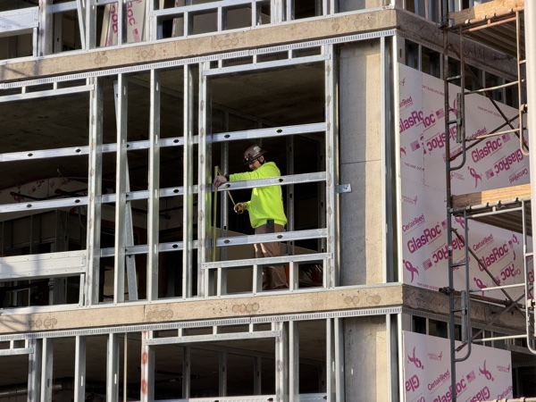 Construction worker measuring steel framing on a job site