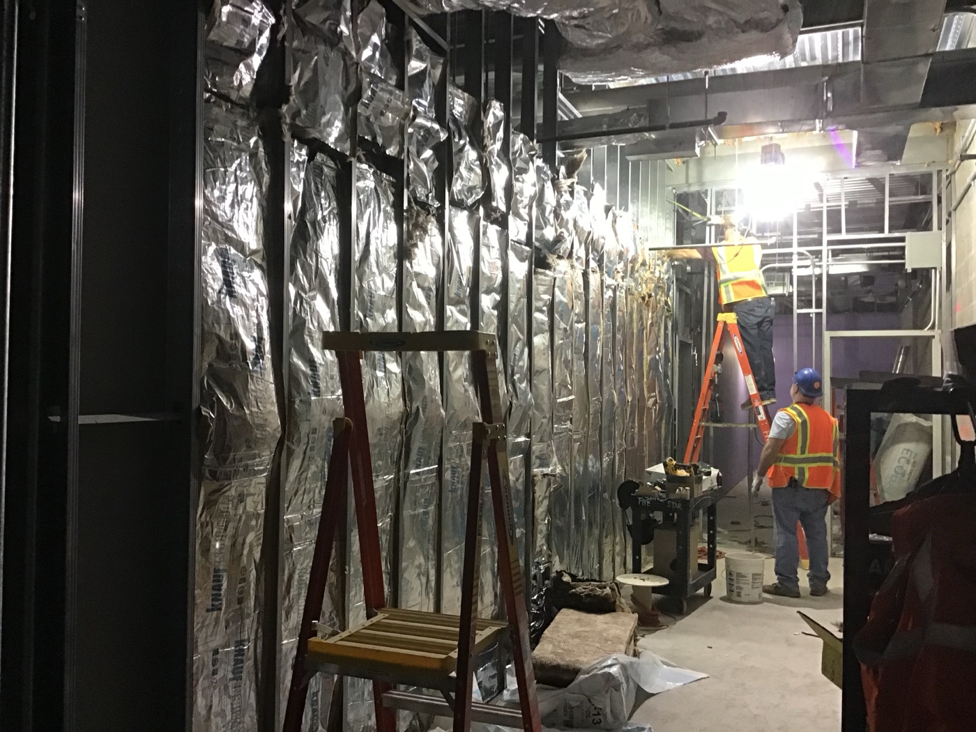 Construction crew installing drywall sheets on interior metal stud framing